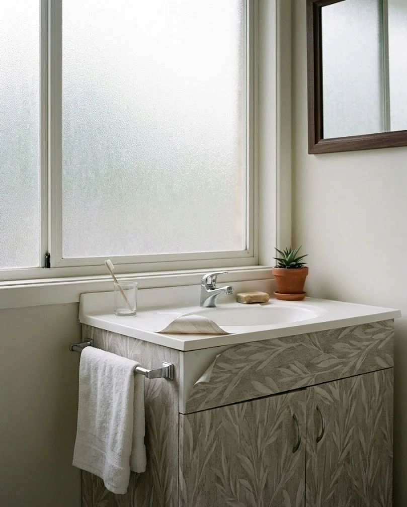 Bathroom vanity wrapped in contact paper with frosted film on the window.