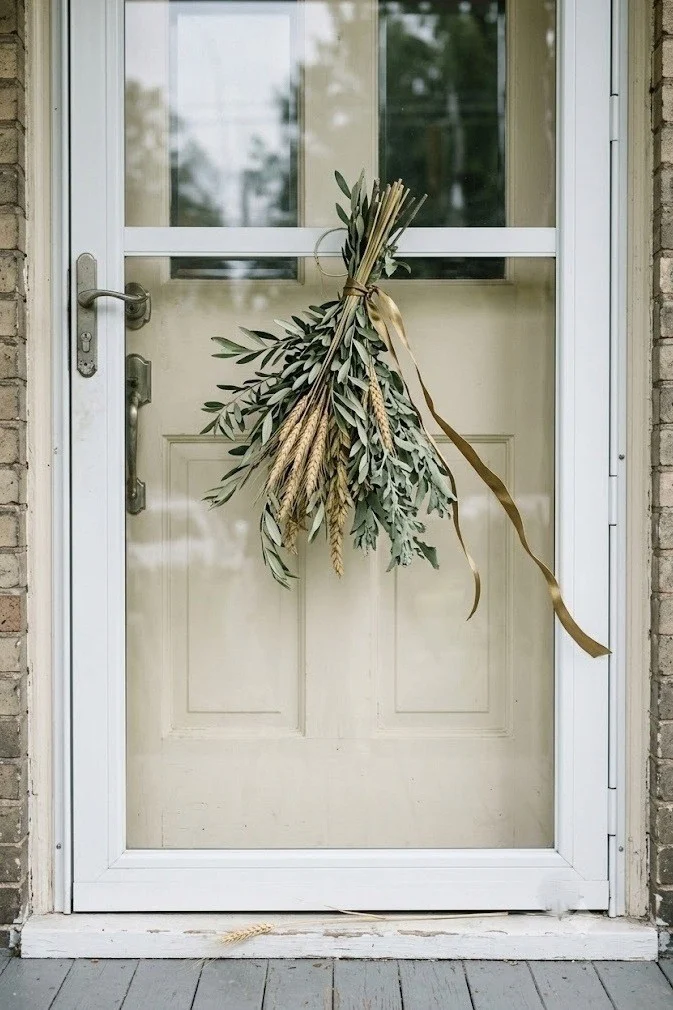 Asymmetric olive and brass door swag on a storm door