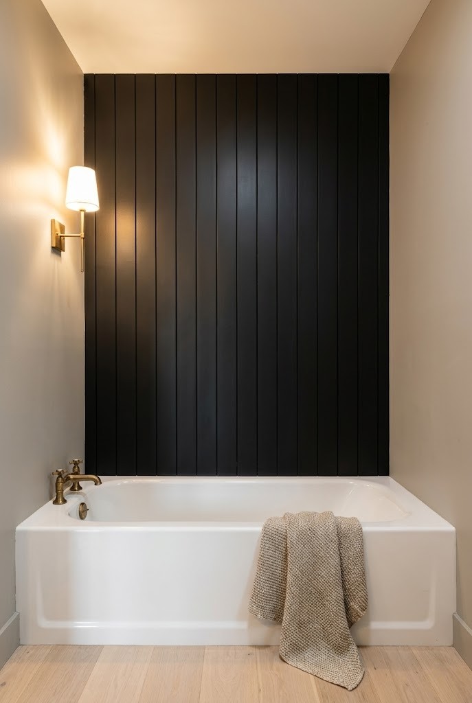 Vertical black shiplap accent wall behind a white alcove tub