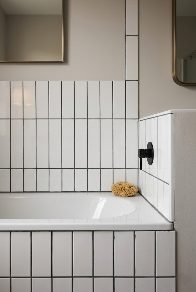 White tub tile regrouted in dark charcoal grout for a moody look