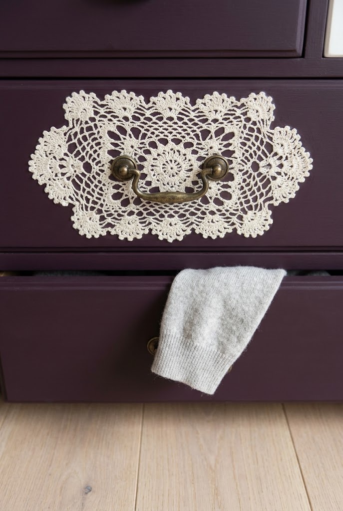 Ivory doily decoupaged onto a deep aubergine drawer front with an aged brass pull