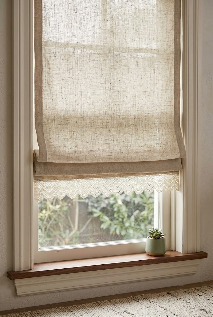 Oatmeal linen roman shade with an ivory lace scalloped border stitched along the hem