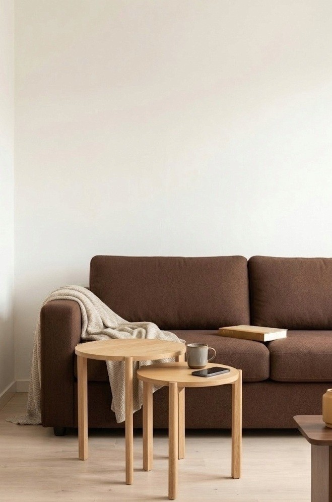 Round pale wood nesting tables beside a brown sofa in a small living room