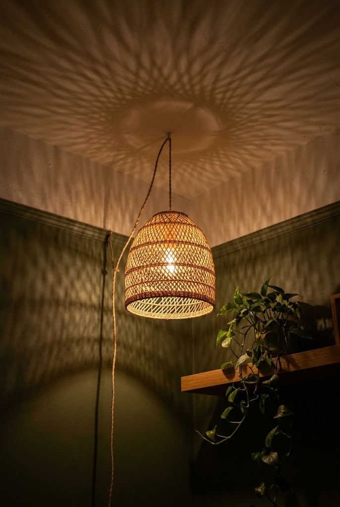 Woven rattan plug-in pendant casting warm patterned shadows across a dim living room ceiling